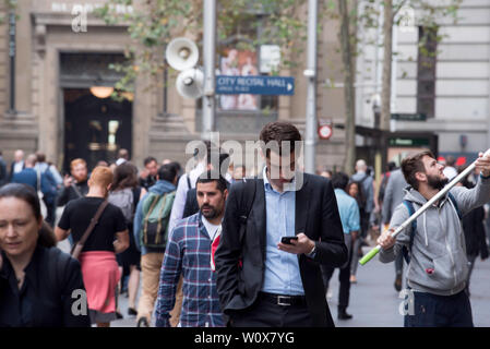 Un detergente per vetri funziona come ora di picco pendolari a piedi lungo la Sydney CBD viale pedonale Martin posto su una fredda mattina di Autunno in Australia Foto Stock