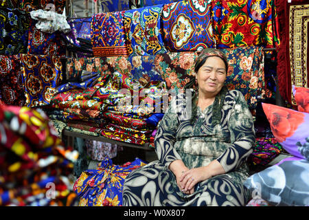 MARGILAN, Valle di Fergana, Uzbekistan - 02 giugno 2019: Uzbek donna abiti di vendita nel mercato Margilan nella valle di Fergana Foto Stock