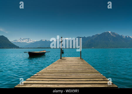 Montreux, VD / Svizzera - 31 Maggio 2019: montagna e lago paesaggio con un vintage canotto di salvataggio e di un molo in legno Foto Stock