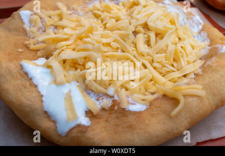 Lángos è un profondo fritto ungherese pane piatto tradizionalmente conditi con formaggio e panna acida. Si tratta di una popolare fast food e street food snack. Foto Stock