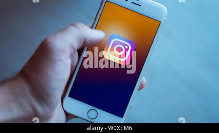 New York / Usa 06-27-2019: l uomo è in possesso di un bianco smartphone con l'icona del instagram rete sociale rappresentata. Foto Stock