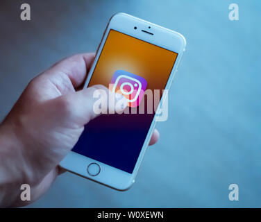 New York / Usa 06-27-2019: l uomo è in possesso di un bianco smartphone con l'icona del instagram rete sociale rappresentata. Foto Stock
