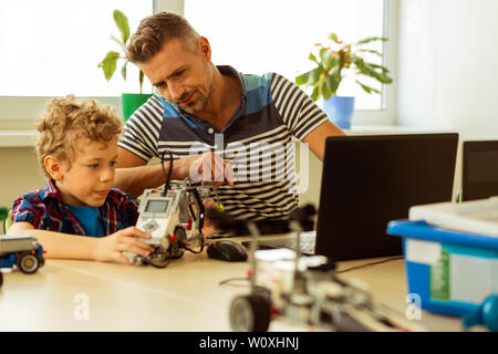Tecnologia dell informazione lezione. Piacevole uomo barbuto seduti insieme con il suo studente pur avendo un information technology lezione Foto Stock