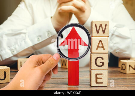 Freccia rossa fino in prossimità dei blocchi di legno con la parola in termini di salari e di un imprenditore. Aumento di stipendio concetto. Tasso salariale. La crescita del fatturato e dei profitti. Successo busi Foto Stock