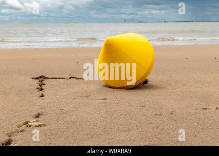 Boa di colore giallo con la bassa marea sulla spiaggia con un gancio rosso fissato Foto Stock