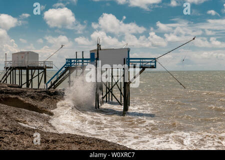 Forme d'onda che ha colpito le coste hard con vecchie case di pescatori in background Foto Stock