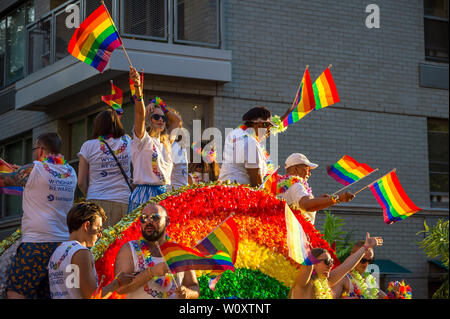 NEW YORK CITY - Giugno 25, 2017: i partecipanti indossano camicie sponsorizzato dalle marche Wyndham e Barclays bandiere d'onda su un galleggiante nel Gay Pride Parade. Foto Stock