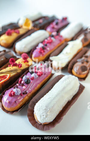 Set di diversi eclairs con vari ripieni e design isolare su uno sfondo bianco, il concetto di cucina francese, copyspace Foto Stock