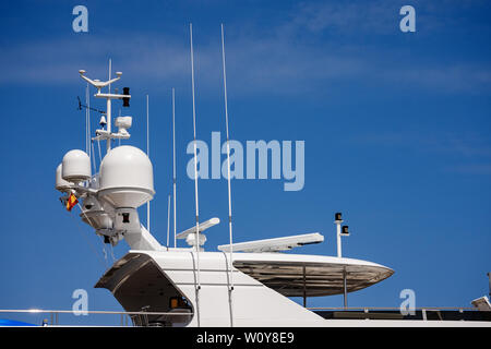 Dettaglio di un lussuoso yacht bianco con apparecchiature di navigazione, radar e antenne sul cielo blu, sovrastruttura Foto Stock