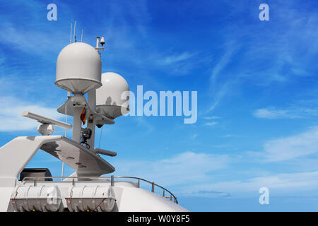 Dettaglio di un lussuoso yacht bianco con apparecchiature di navigazione, radar e antenne sul cielo blu, sovrastruttura Foto Stock