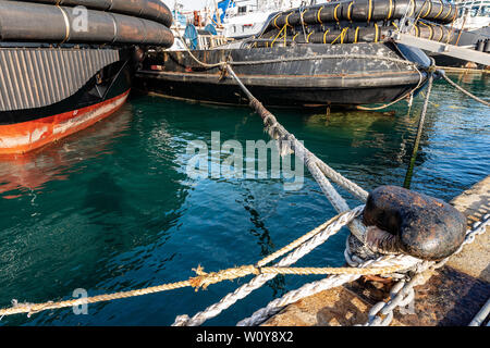 Le navi ormeggiate nel porto - nero grande bollard ormeggio con funi o cime sulla banchina del porto. La Spezia, Italia Foto Stock