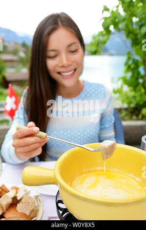 La Fonduta di formaggio - donna locale mangiando cibo svizzero intingere il pane nel formaggio fuso. Persone mangiare cibo tradizionale dalla Svizzera divertimento dal lago delle Alpi sul viaggio in Europa. Foto Stock