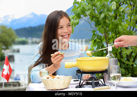 Persone mangiare la fonduta di formaggio svizzero a cena in Svizzera dal lago nelle Alpi. Donna di mangiare il cibo locale avendo divertimento su viaggi in Europa. Coppia romantica all'aperto in estate. Foto Stock