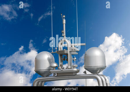 Dettaglio di lusso yacht grigio con apparecchiature di navigazione, radar e antenne sul cielo blu con nuvole Foto Stock