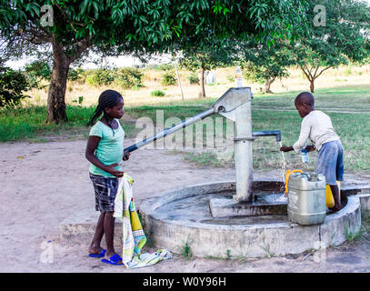 Gli alunni di acqua potabile e la riproduzione in comunità a mano la pompa di acqua in Africa Foto Stock