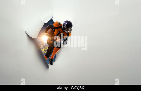 Un foro in un foglio di carta con un giocatore di football americano in azione Foto Stock