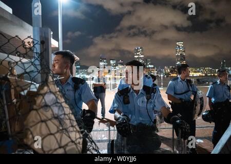 Gli ufficiali di polizia visto custodire l'appezzamento di terreno nel centro di Waterfront che per essere trasferiti ai cinesi Esercito del popolo. Centinaia di manifestanti rally contro il governo di trasferimento di un appezzamento di terreno sul lungomare centrale per il popolo cinese della Esercito di Liberazione (PLA) come un militare di dock. Pro-democrazia dimostranti di Hong Kong hanno organizzato manifestazioni nelle scorse settimane, per chiedere il ritiro di un controverso disegno di legge in materia di estradizione, le dimissioni del territorio è chief executive Carrie Lam, un'indagine polizia brutalità e goccia riot accuse contro manifestanti pacifici. Foto Stock