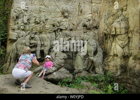 Donna usa il suo smartphone per scattare foto di una bambina di fronte al rilievo abbandonato "Adorazione dei Magi" nella zona dell'aria aperta la galleria scultoreo noto come Braunův Betlém (Braun di Betlemme) nella foresta vicino al villaggio di Žireč in Boemia orientale, Repubblica Ceca. Il rilievo monumentale è stato scolpito da famosi-austriaco nato scultore Matthias Bernhard Braun (Matyáš Bernard Braun) dal 1726 al 1734 tra le altre statue e rilievi direttamente nelle rocce di arenaria nella nuova foresta vicino ospedale di Kuks (Nový les Kuksu u). Il Braunův Betlém è considerato uno dei capolavori Foto Stock