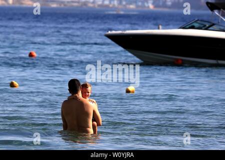 (190628) -- Aqaba (Giordania), 28 giugno 2019 (Xinhua) -- i turisti di godersi il tempo libero vicino alla spiaggia del Mar Rosso nel sud della città portuale di Aqaba, Giordania, il 28 giugno 2019. Aqaba attira turisti da Giordania e all'estero per godersi le vacanze estive con le sue famose spiagge e vari sport acquatici. (Xinhua/Mohammad Abu Ghosh) Foto Stock