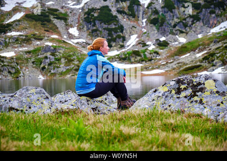 Ritratto di una donna malinconico escursionisti in montagna lago Bucura, in Retezat montagne (parte dei Carpazi), Romania, in serata, con acque calme, Foto Stock