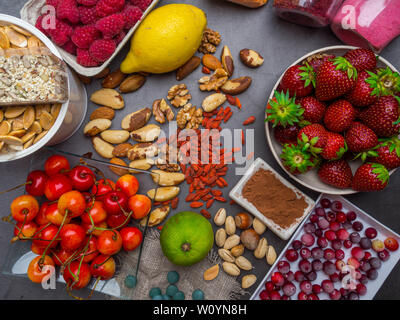 Cibo sano e pulito mangiare selezione: semi, superfoods, verdura e frutta in polvere di cemento grigio Sfondo, close up Foto Stock