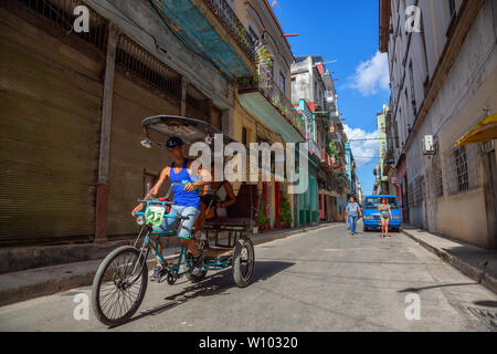 L'Avana, Cuba - 13 Maggio 2019: Noleggio Taxi Driver in bici per le strade di l'Avana Vecchia Città durante un vivace e luminosa mattina di sole. Foto Stock