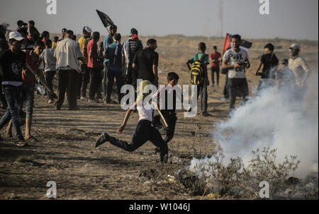 Un dimostrante palestinese getta le scatole metalliche del gas lacrimogeno durante gli scontri.palestinesi si sono scontrati con le forze israeliane durante una manifestazione di protesta che chiede di porre fine al blocco israeliano della Striscia di Gaza e rivendicano il diritto di tornare alle loro case durante la recinzione di confine tra Israele e la striscia di Gaza nel sud della striscia di Gaza. Foto Stock