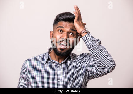 Infastiditi uomo indiano slapping fronte e dare la colpa a se stesso. Spiacevoli bello dai capelli scuri uomo che indossa il denim shirt gesticolando e guardando la fotocamera. Foto Stock