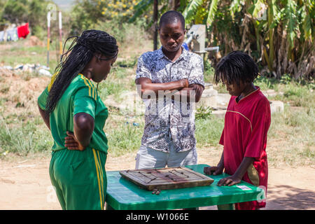 Tradizionale strategia africana board game sapere come morabaraba o muravarava essendo giocato su una tavola di legno con tappo di bottiglia pezzi Foto Stock