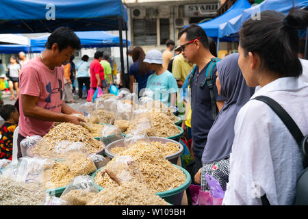 KOTA KINABULU, BORNEO - Giugno 2 Pesci secchi venditore in Kota Kinabalu Gaya Street domenica mercato prodotto confezioni per il compratore e mani sopra. Foto Stock