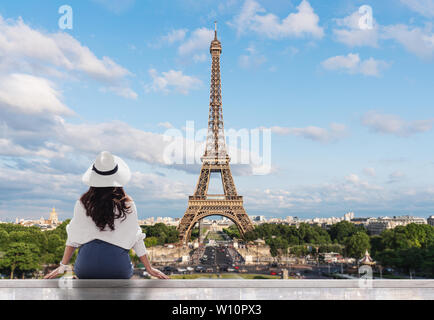 Giovane donna di viaggiatori nel cappello bianco guardando la torre Eiffel, famoso punto di riferimento e meta di viaggio a Parigi Foto Stock