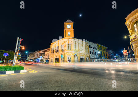 Phuket, Tailandia - 2018 Dic 12 : Punto di riferimento di clock di giallo edificio a torre con traffico su crossway di notte Foto Stock