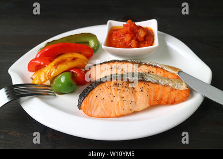 Piatto sano di grigliate di filetti di salmone con verdure colorate servita su legno marrone scuro tabella Foto Stock