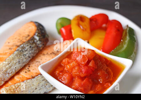 Ciotola di deliziosa salsa di pomodoro per grigliate di filetti di salmone Foto Stock