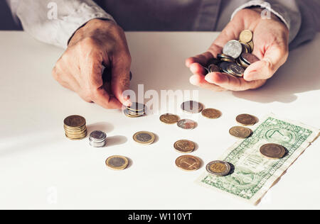 Dollaro e monete in vecchia donna le mani su sfondo bianco con spazio di copia Foto Stock