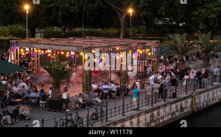 Berlino, Germania. Il 28 giugno, 2019. Numerose persone godetevi la serata al bar sulla spiaggia Mitte presso il Bodemuseum, non lontano dal parco di Monbijou. Le offerte speciali sulle rive del fiume Spree è una pista da ballo dove si può ballare aria aperta a una vasta gamma di stili musicali. Credito: Paolo Zinken/dpa/Alamy Live News Foto Stock