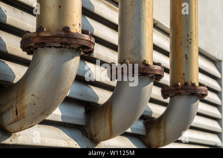 Il punto di collegamento della tubazione di tre condotti di ventilazione di sfiato per il fumo al di fuori dell'edificio, rusty superficie che circonda con la luce del sole e lo in alluminio Foto Stock