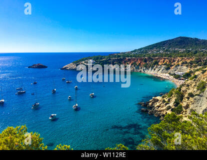 Bella vista aerea sulla spiaggia cala d'Hort, barche e yacht, il blu del cielo e del mare. Ibiza, Isole Baleari, Spagna. Foto Stock