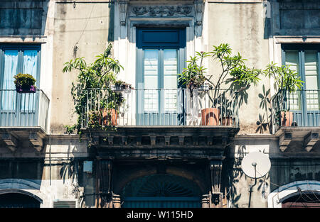 Balcone con vasi da fiori e piante di casa in un edificio storico a Catania, architettura tradizionale della Sicilia, Italia Foto Stock