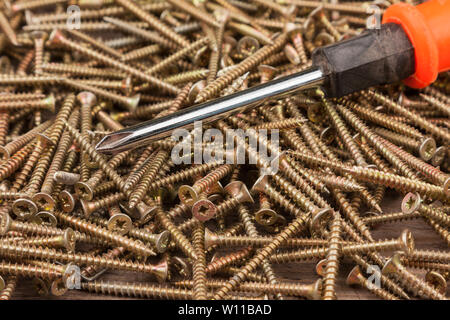 Cacciavite giacente su un mucchio di viti. L'attrezzo e attrezzature Foto Stock