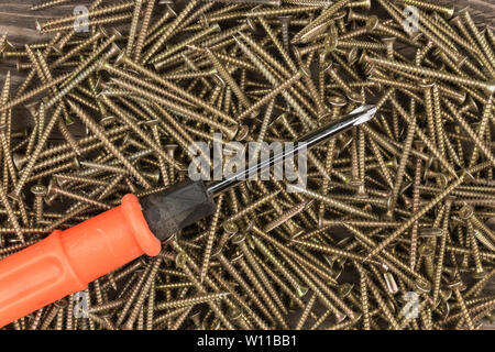 Cacciavite giacente su un mucchio di viti. Vista dall'alto. Utensili e attrezzature. Foto Stock