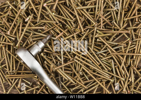 Cacciavite giacente su un mucchio di viti. Vista dall'alto. Utensili e attrezzature. Foto Stock