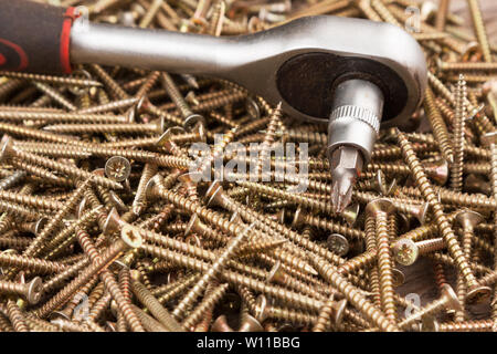 Cacciavite giacente su un mucchio di viti. L'attrezzo e attrezzature Foto Stock