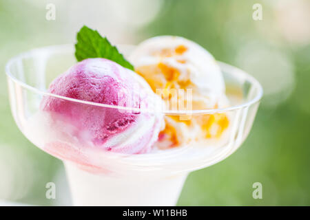 Due differenti palline di gelato in una ciotola di vetro - outdoor. Commestibile reale gelato - Senza ingredienti artificiali utilizzati Foto Stock