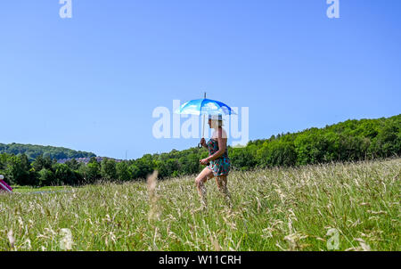 Brighton Regno Unito 29 Giugno 2019 - Una giovane donna rimane in ombra sotto il suo ombrello come lei cammina attraverso Stanmer Park in Brighton oggi nel caldo clima soleggiato come un ondata di caldo si diffonde in tutta la Gran Bretagna con temperature attese per raggiungere la metà degli anni trenta in alcune parti del paese Credito: Simon Dack / Alamy Live News Foto Stock