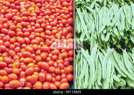 Piccoli pomodori e fagioli verdi per la vendita su un mercato Foto Stock