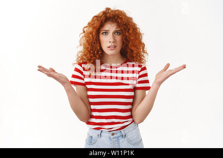 Che cosa è errato. Redhead, curly-haired Giovani freak out lamenta donna sostenendo scrollare sgomento alzare le mani lateralmente perplesso interrogato bothe cringing Foto Stock