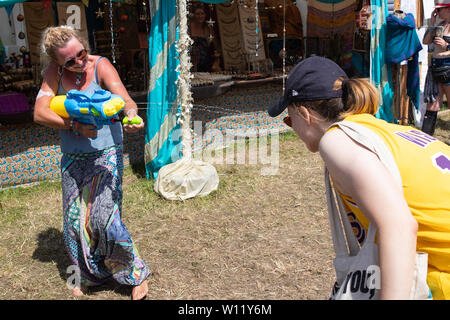 I frequentatori del festival sono state spruzzate con una pistola ad acqua per raffreddare a Glastonbury Festival presso l'azienda agricola degna in Pilton, Somerset. Foto Stock