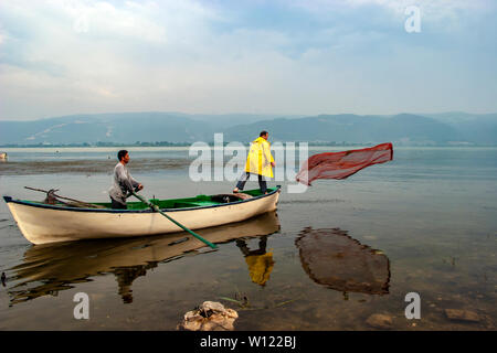 Bursa, Turchia - 26 maggio 2007; i pescatori è gettando rete da pesca al lago dalla barca nel lago Uluabat, Golyazi Foto Stock