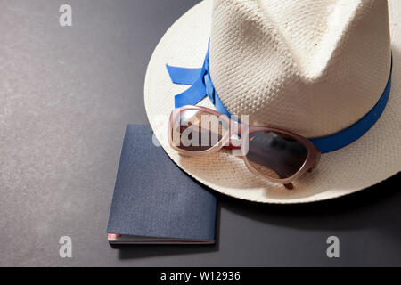 Passaporto, cappello e occhiali da sole su sfondo nero Foto Stock